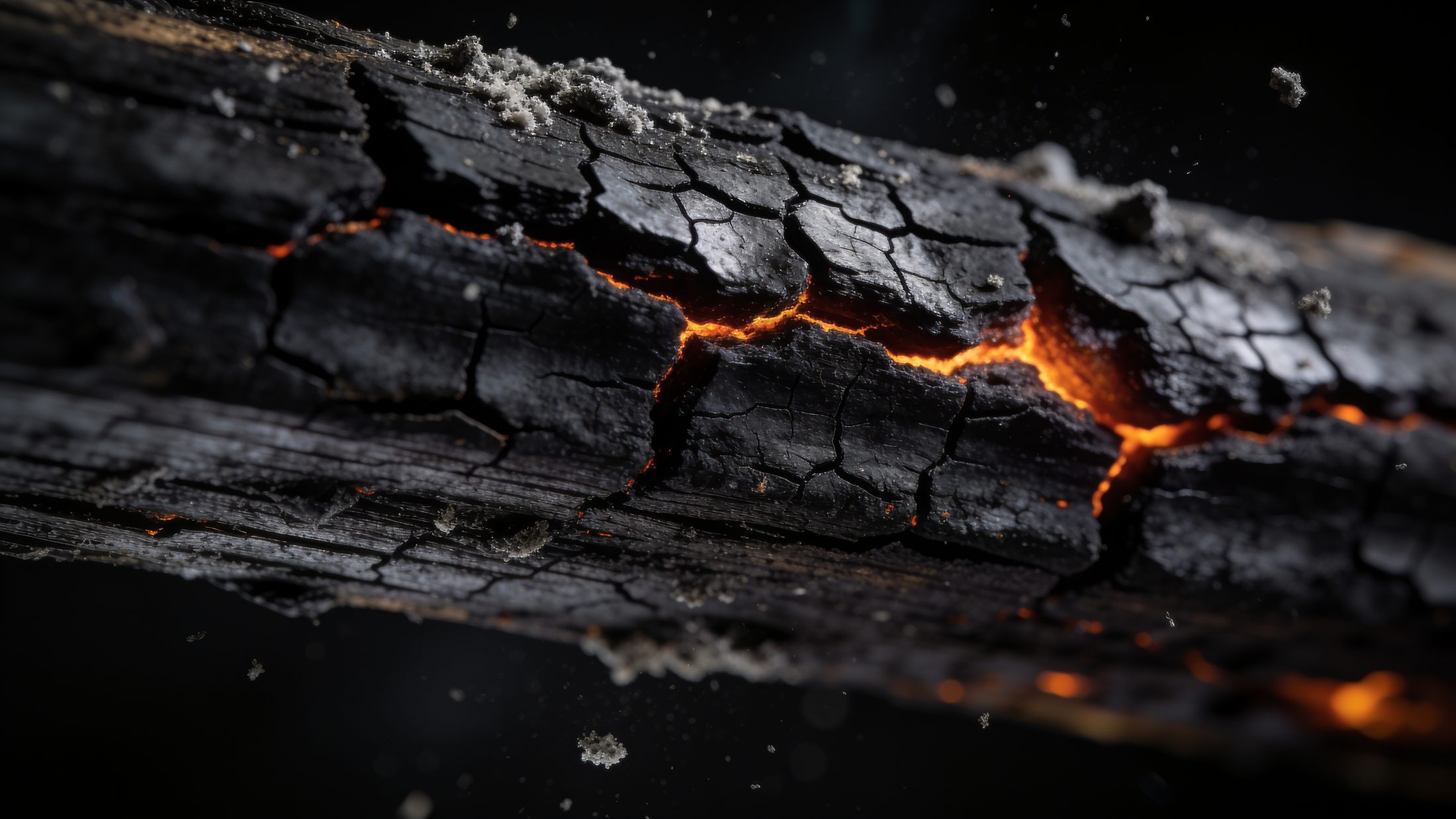 Close-up of a charred ceiling joist with embers in the cracks